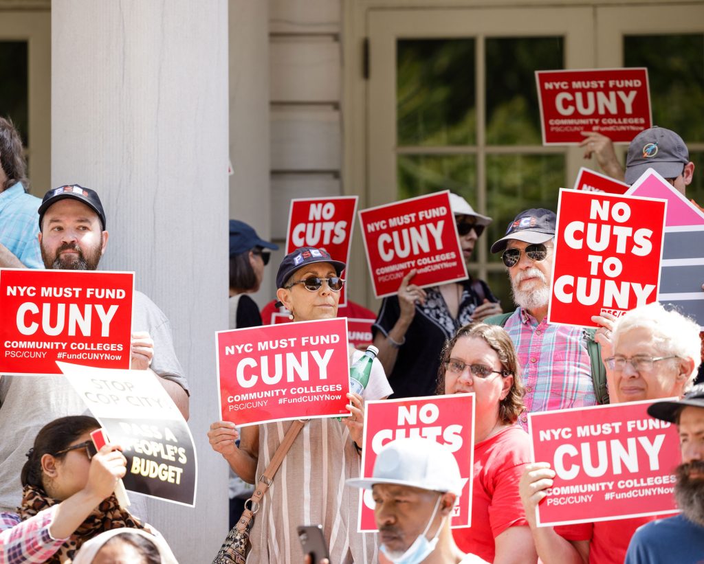 Members hold signs saying "No Cuts to CUNY" and "NYC Must Fund CUNY" at city hall