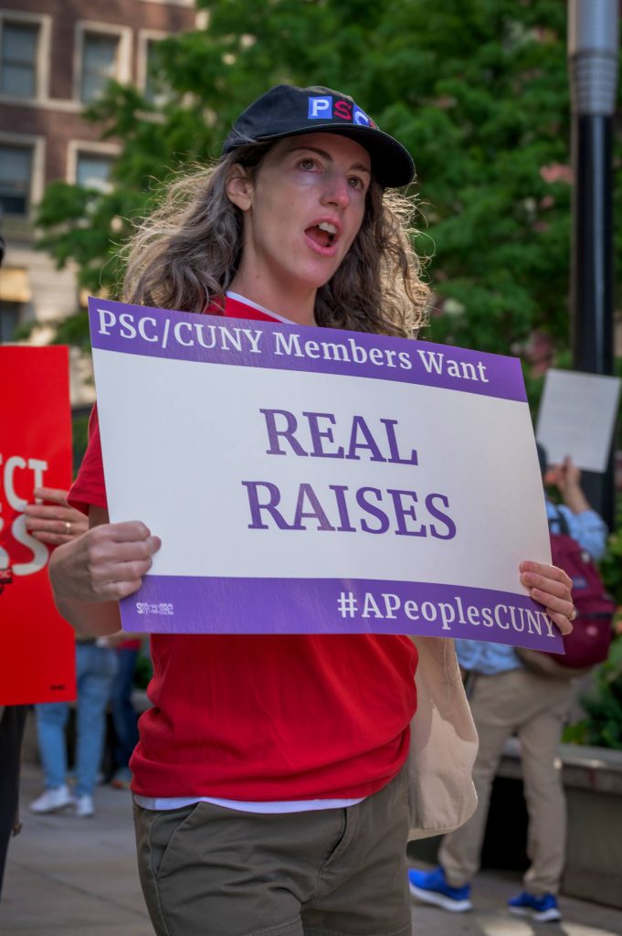 Member holds "REAL RAISES" sign