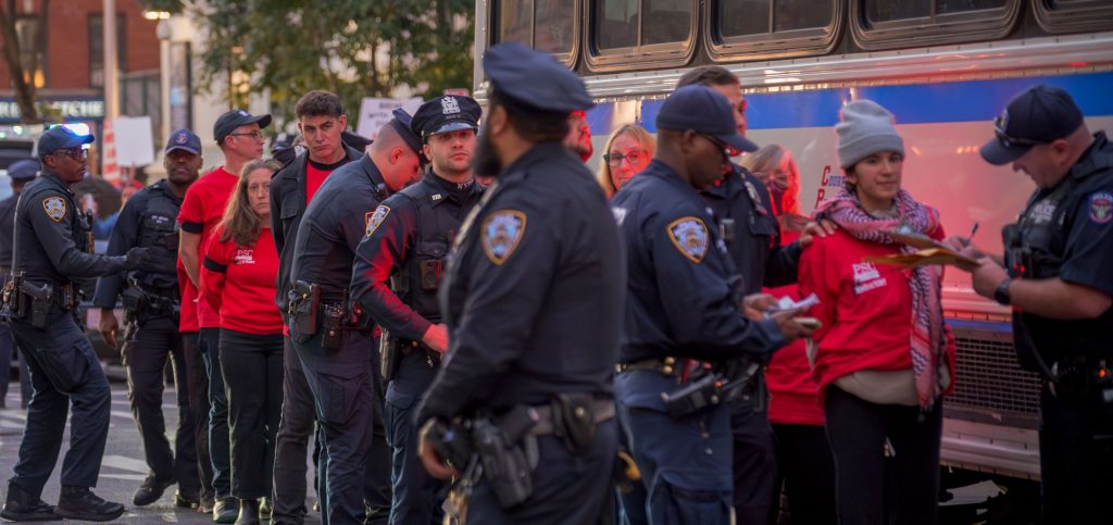 NYPD officers line up PSC arrestees to put them on police bus 