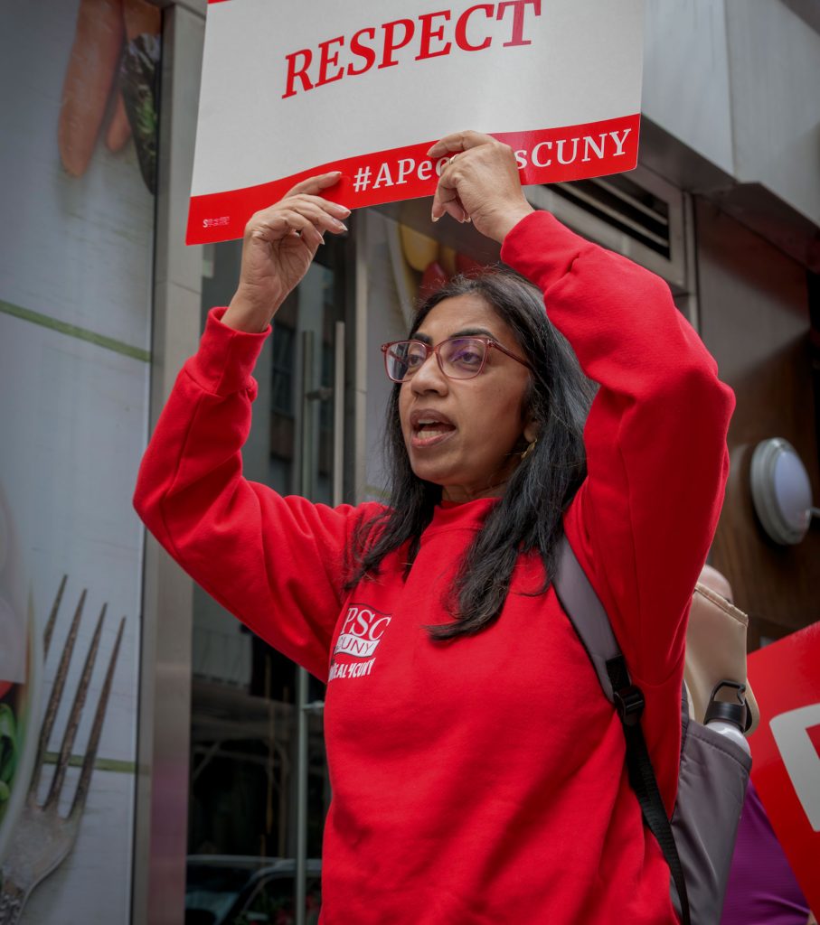 Woman in red PSC sweatshirt holds up "respect" sign